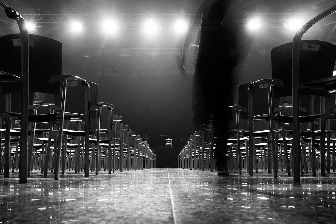 Rows of chairs and spotlights on an empty stage.